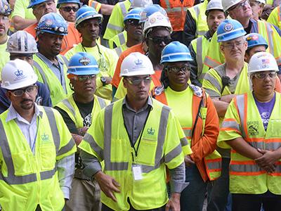 diverse construction workers standing in hard-hats and neon yellow work vests